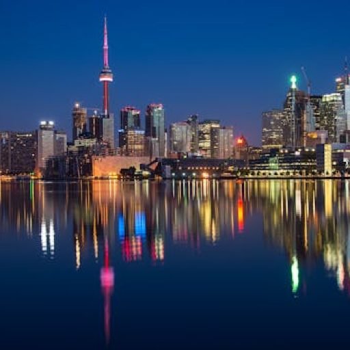 Stunning night view of Toronto skyline reflecting on water with CN Tower prominent.